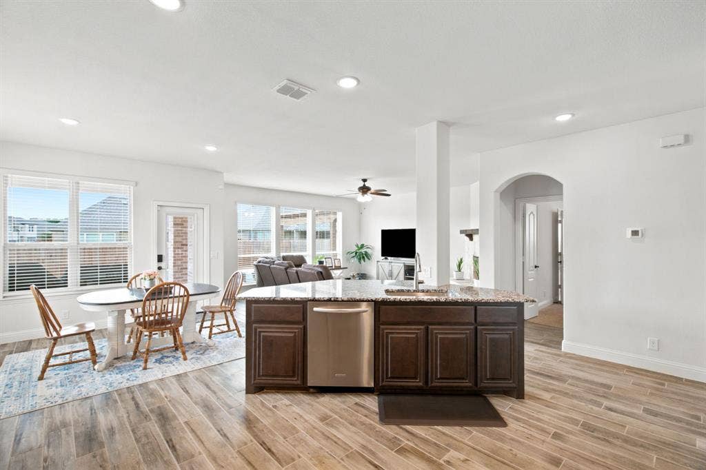 1218 Misty Ridge Drive, Justin, TX 76247 Open-concept kitchen and dining area featuring wood-look tile flooring, recessed lighting, a kitchen island with built-in cabinetry, and stainless steel dishwasher