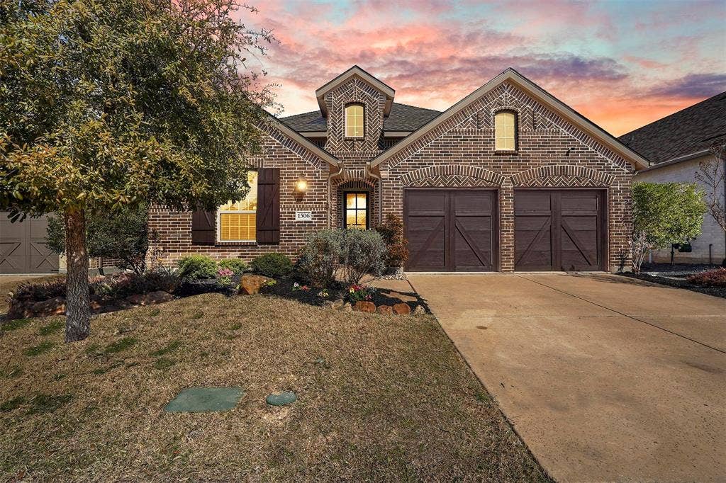 1506 Carnation Street, Celina, TX 75078 Brick exterior with architectural details, two-car garage with wood-finish doors, landscaped front yard, and a concrete driveway