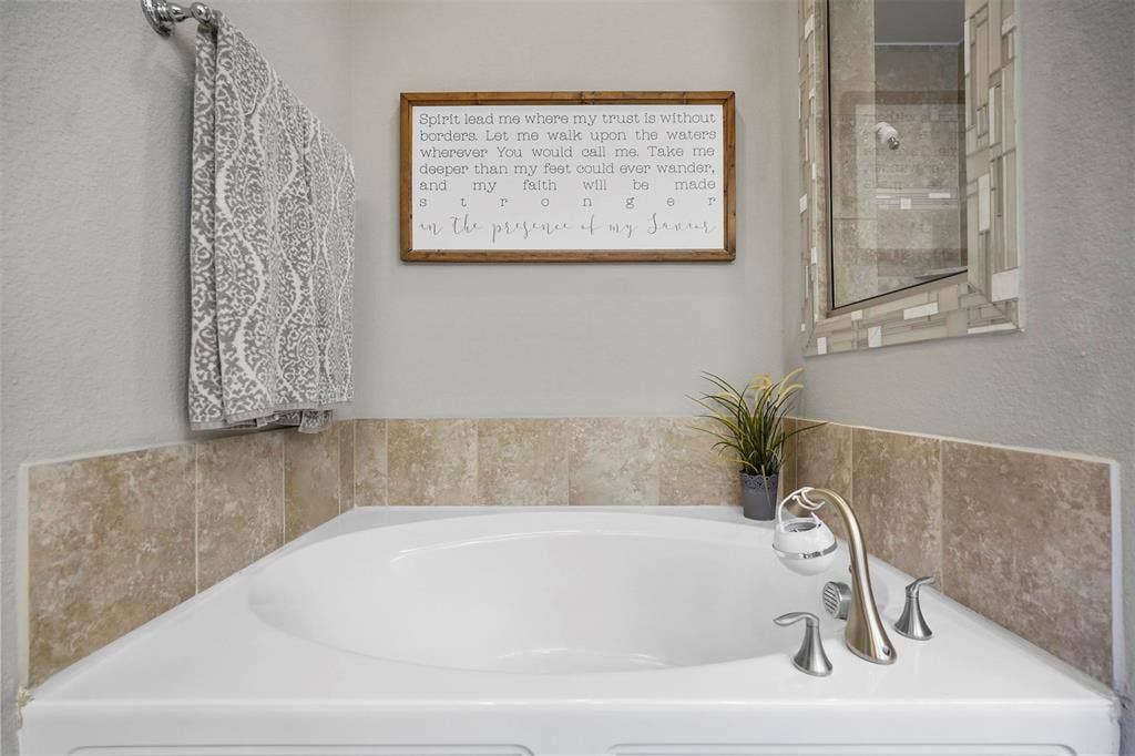 1506 Carnation Street, Celina, TX 75078 Corner soaking tub with deck-mounted faucet fixtures and stone-finish tile surround