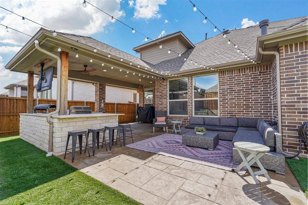 1506 Carnation Street, Celina, TX 75078 Expansive patio featuring a built-in outdoor kitchen with stone-finish base, covered seating area, and stamped concrete flooring