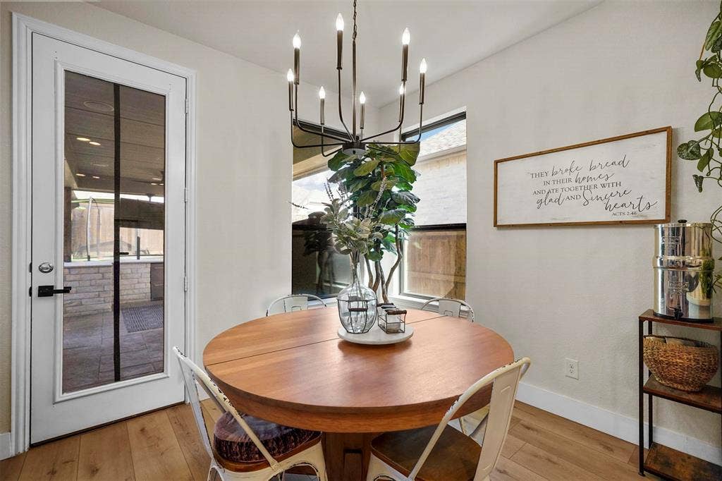 1506 Carnation Street, Celina, TX 75078 Wood-finish flooring, a full-lite glass panel door with matte black hardware, a rectangular window, and a chandelier with candelabra bulbs