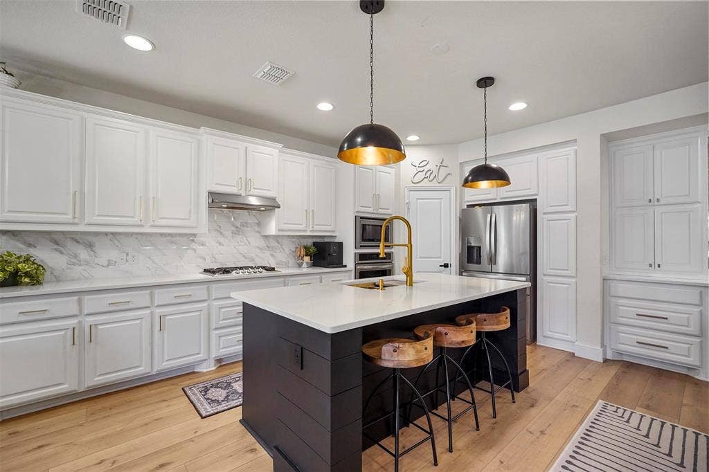 1506 Carnation Street, Celina, TX 75078 Gourmet kitchen with a large center island, white shaker-style cabinetry, stainless steel appliances, and wood-finish flooring