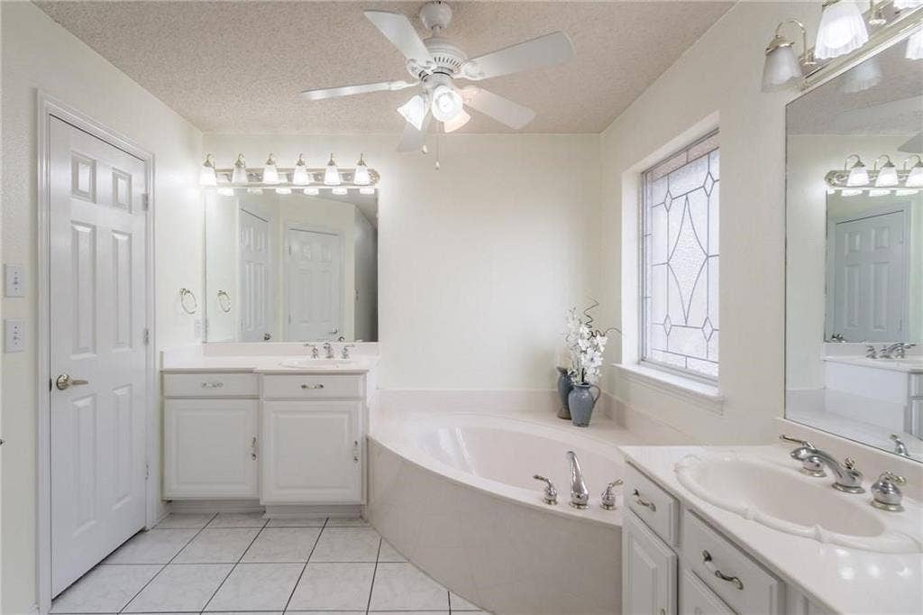 5000 Pointclear Court, Arlington, TX 76017 Dual vanity sinks, built-in soaking tub, decorative privacy window, ceiling fan with integrated lighting, and tile flooring