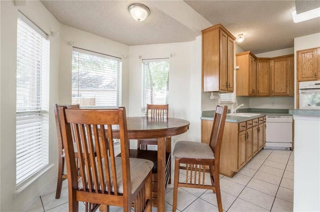 5000 Pointclear Court, Arlington, TX 76017 Bay window with blinds, recessed lighting, tile flooring, oak cabinetry, and integrated appliances