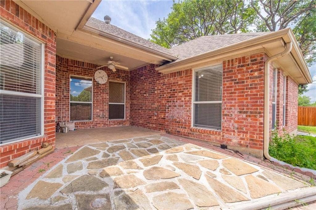 5000 Pointclear Court, Arlington, TX 76017 Covered patio featuring a stone slab surface, brick exterior, and a ceiling fan