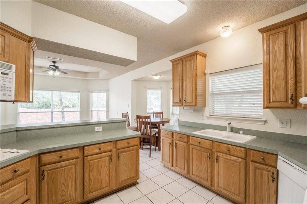 5000 Pointclear Court, Arlington, TX 76017 Kitchen with wood cabinetry, light-toned countertops, a built-in double basin sink, and tile flooring