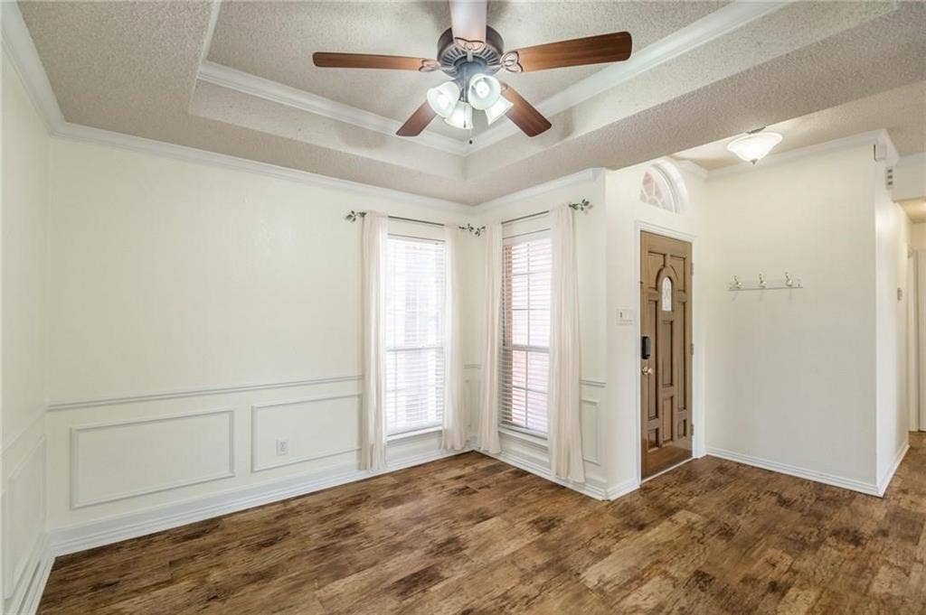 5000 Pointclear Court, Arlington, TX 76017 Tray ceiling with crown molding, wood-finish flooring, wainscoting, and a decorative front door with an arched transom