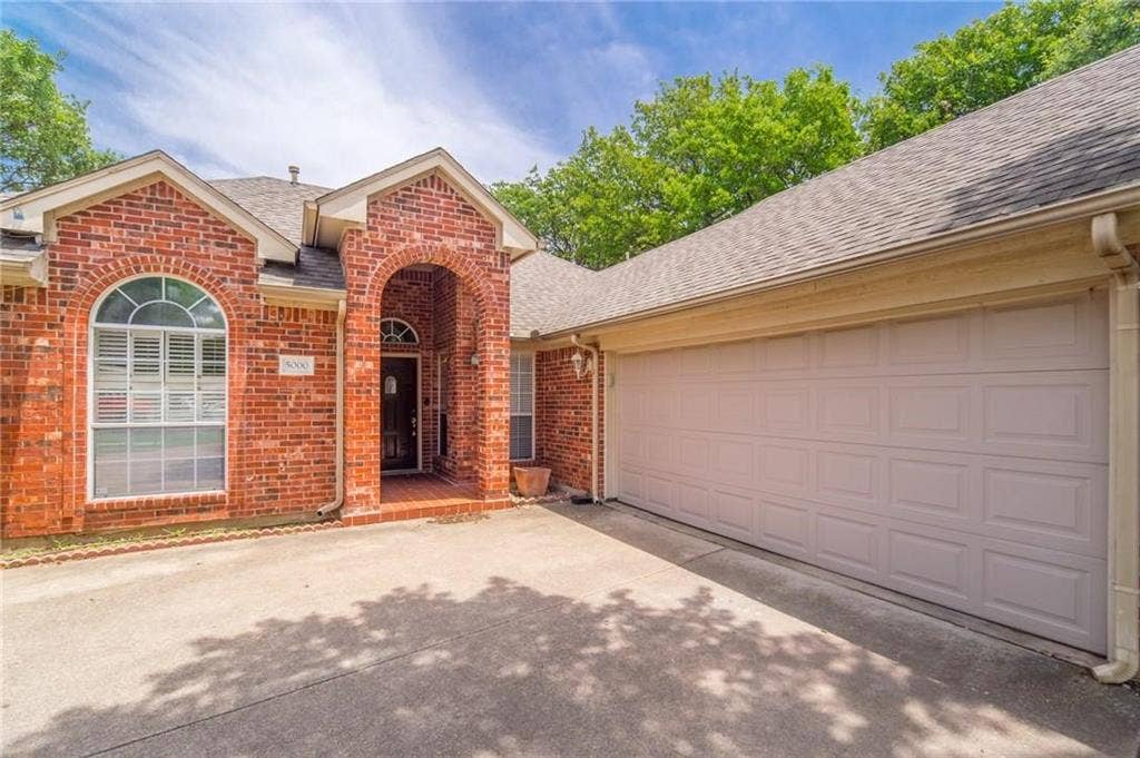 5000 Pointclear Court, Arlington, TX 76017 Brick exterior with an arched entryway, arched window, and a two-car garage
