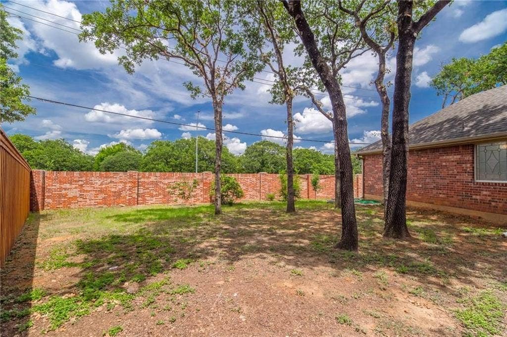 5000 Pointclear Court, Arlington, TX 76017 Expansive yard featuring mature trees, a full brick perimeter wall, and a wood-paneled fence