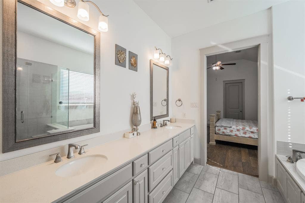 Dual vanity with gray cabinetry, white countertops, brushed nickel fixtures, and framed mirrors