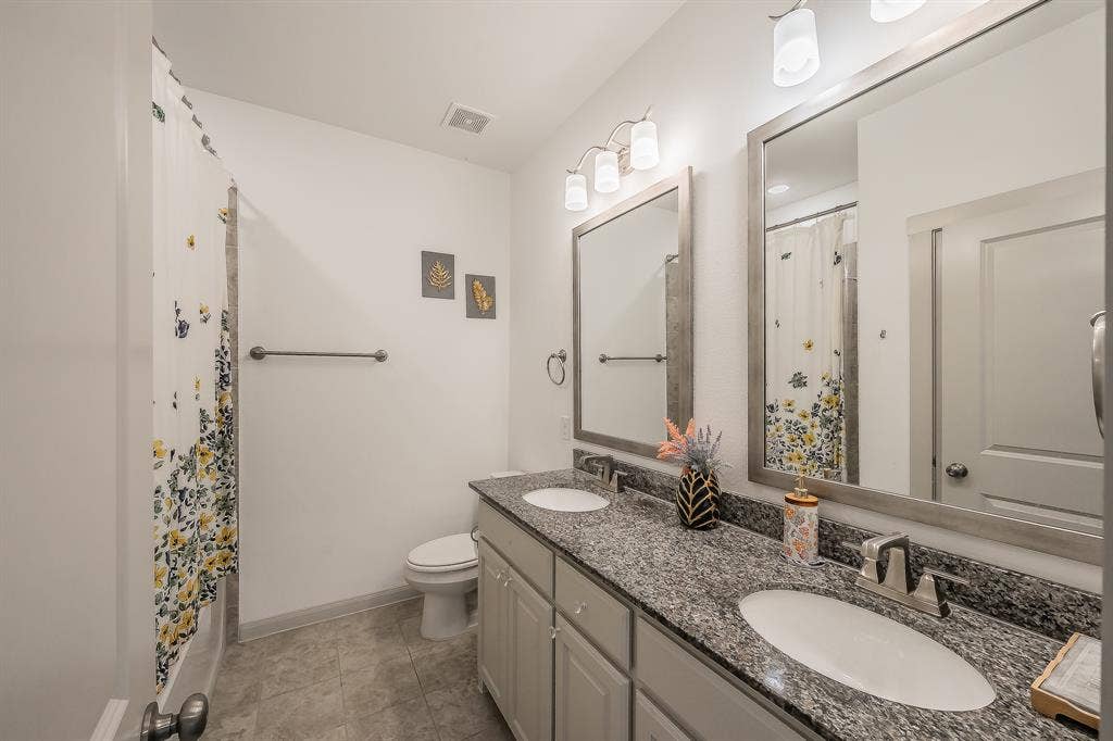 Dual sink vanity with granite countertop, undermount sinks, and framed mirrors, with plenty of storage