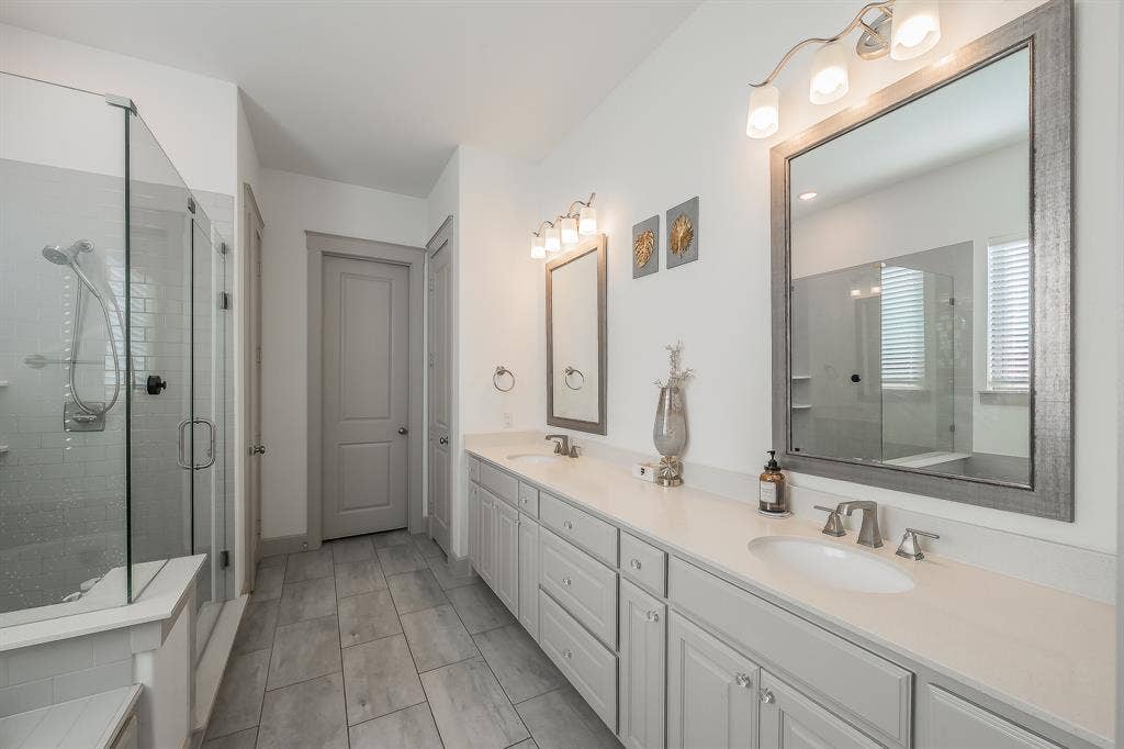 Dual sink vanity with plenty of storage, quartz countertops, and framed mirrors