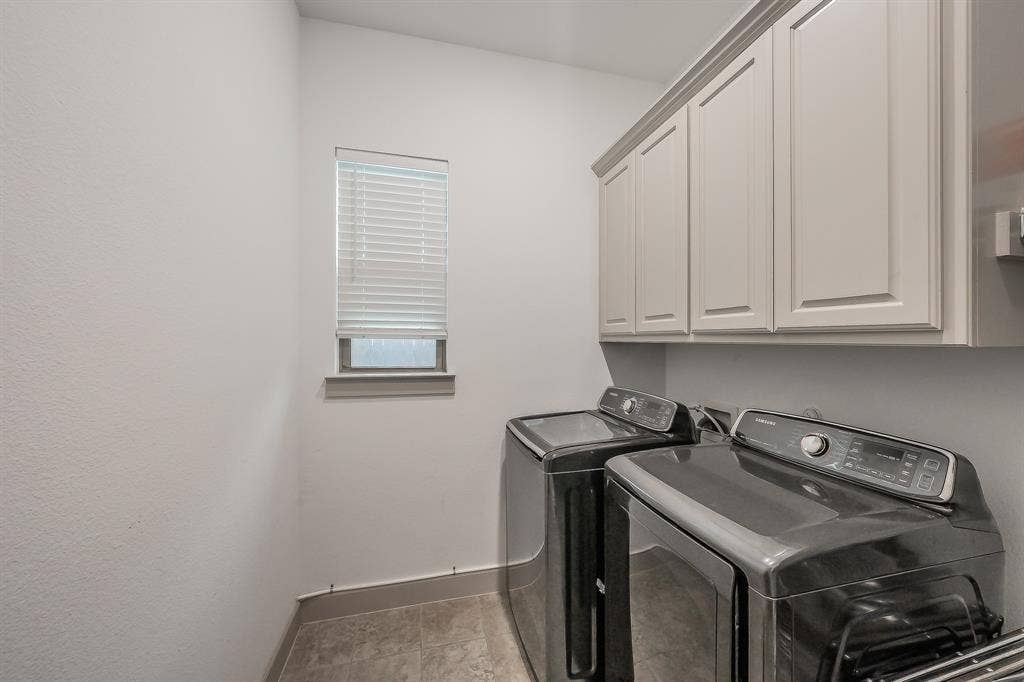 Dedicated spacious laundry room featuring built-in cabinetry and a high-set window for natural light and ventilation