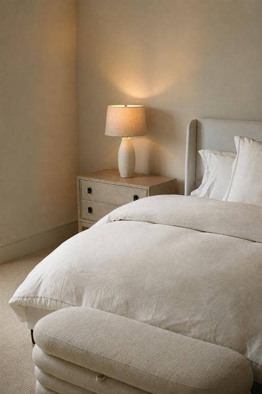Upholstered winged headboard with a light wood-finish nightstand featuring dark hardware