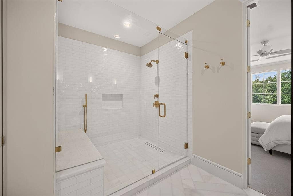 Glass-enclosed shower with subway tile, built-in bench, recessed niche, and gold-finish fixtures