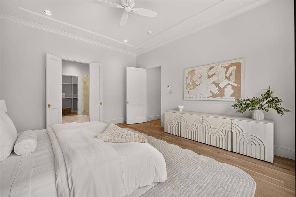 Tray ceiling with recessed lighting, ceiling fan, wide plank wood-finish flooring, and white paneled doors