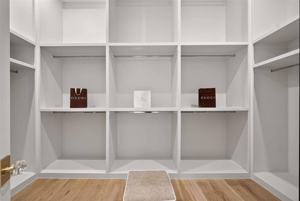 Built-in white shelving, integrated hanging rods, wood-finish flooring, and a crystal-knob door handle