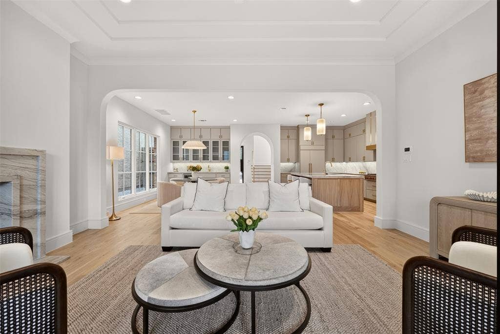 Coffered ceiling, wood-finish flooring, stone-clad fireplace, arched doorways, and recessed lighting