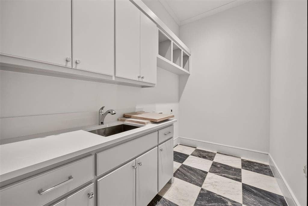 White cabinetry, a stainless steel sink, a chrome faucet, and a black and white checkerboard floor