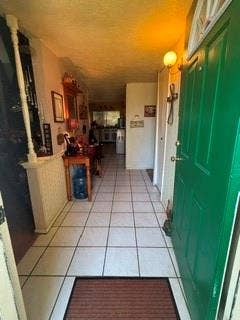 Tiled entryway with a solid panel door and a wall-mounted light fixture