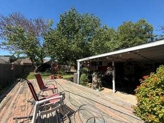 Expansive wood-finish deck with a covered patio structure, mature trees, and privacy fencing