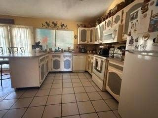 U-shaped kitchen with tile flooring, extensive cabinetry, built-in dishwasher, and a double basin sink