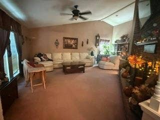 Vaulted ceiling with an integrated ceiling fan, brick fireplace, and wall-mounted lighting fixtures