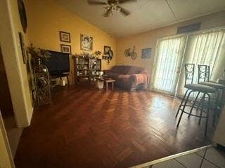 Vaulted ceiling with a ceiling fan, wood-finish flooring with a herringbone pattern, and a sliding glass door