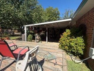 Expansive wood deck with a covered patio area, mature trees, and brick exterior