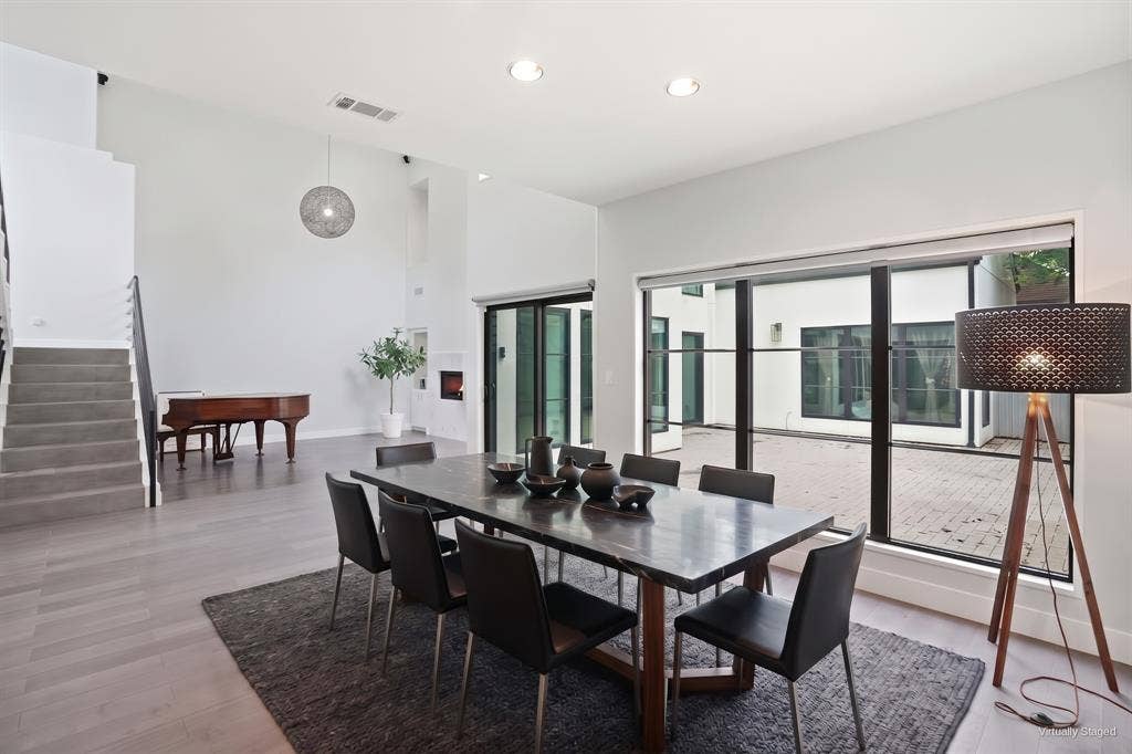 9123 Valley Chapel Lane, Dallas, TX 75220 Open dining and living space with a wall of black-framed glass looking out to the private courtyard. Virtually staged.
