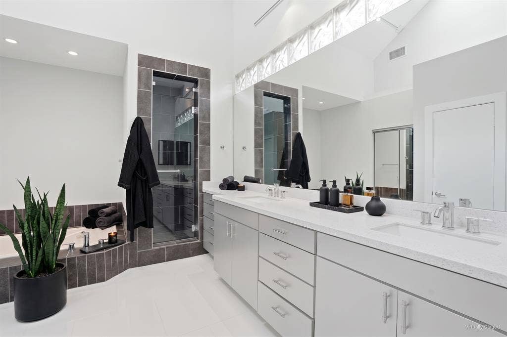 9123 Valley Chapel Lane, Dallas, TX 75220 Primary bath with dual sinks, quartz countertops, an extended vanity, and glass-block clerestory windows. Virtually staged.
