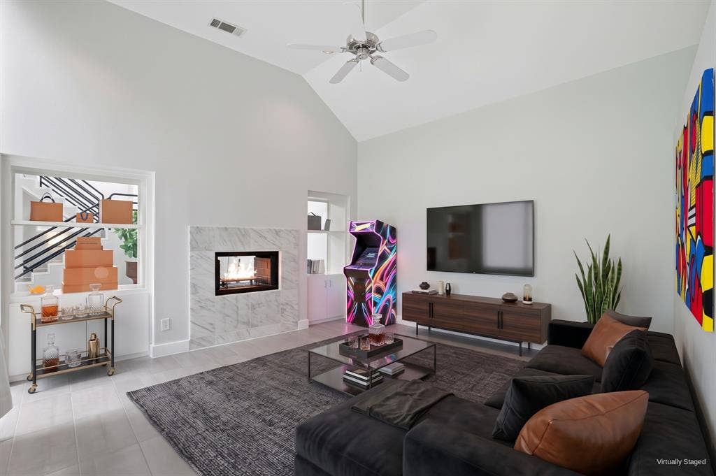 9123 Valley Chapel Lane, Dallas, TX 75220 Family room with a double-sided marble gas fireplace that also opens to the stairwell, plus built-in storage. Virtually staged.