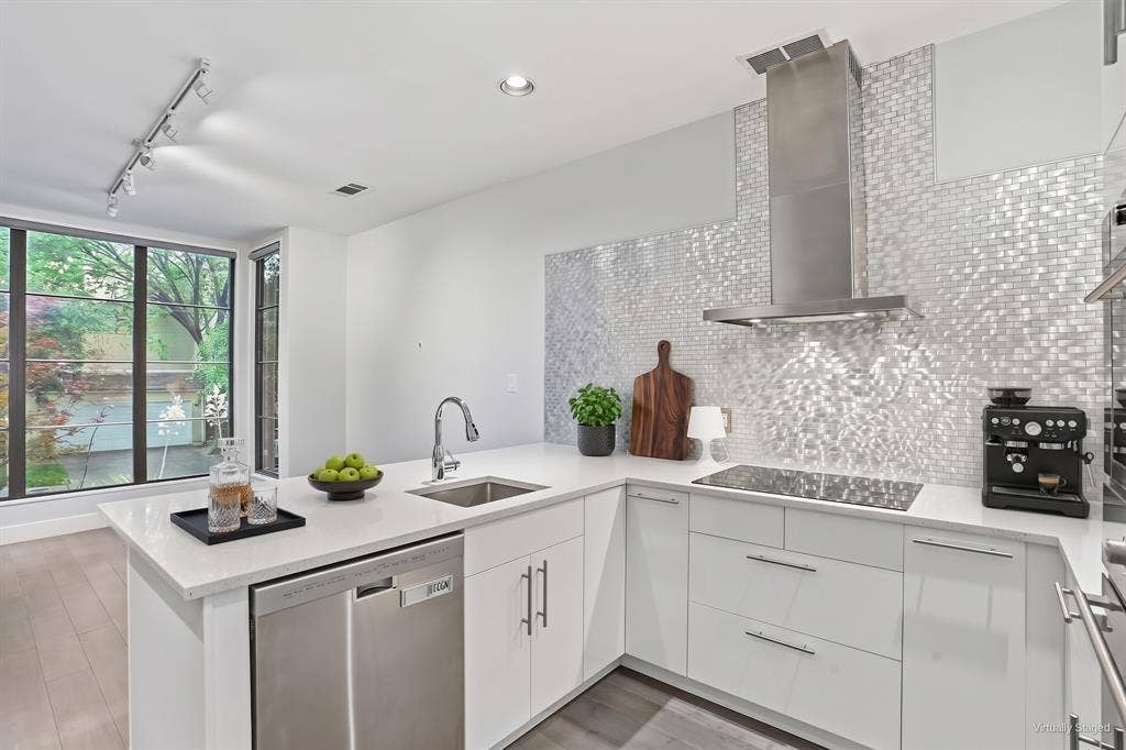 9123 Valley Chapel Lane, Dallas, TX 75220 Updated kitchen with quartz countertops, a shimmering mosaic tile backsplash, stainless chimney hood, and high-gloss white cabinetry. Virtually staged.
