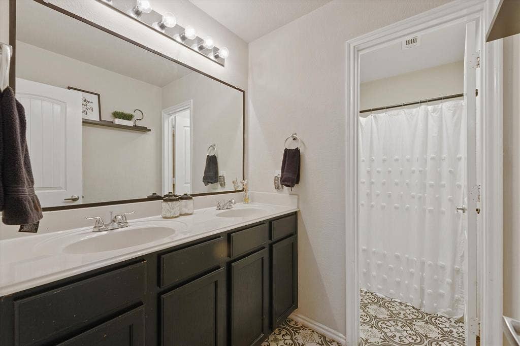 2053 Lake Trail Drive, Heartland, TX 75126 Dual vanity with undermount sinks, stone-look countertop, and dark cabinetry