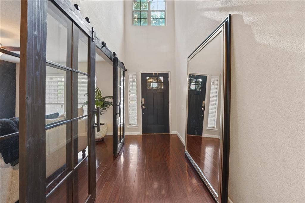 2053 Lake Trail Drive, Heartland, TX 75126 Hardwood-style flooring, high vaulted ceilings, transom window, and paneled barn doors with glass inserts
