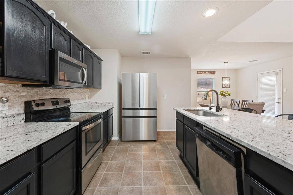 2053 Lake Trail Drive, Heartland, TX 75126 Kitchen featuring dark cabinetry, light-colored countertops, stainless steel appliances, and tile flooring