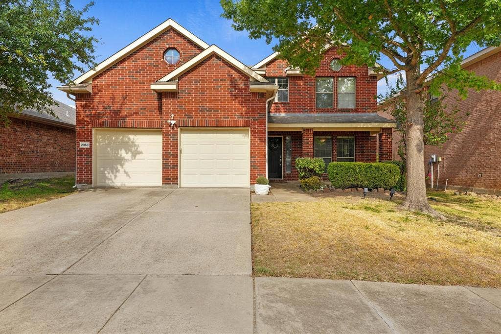 2053 Lake Trail Drive, Heartland, TX 75126 Red brick exterior with white trim, a covered entry porch, and a two-car garage