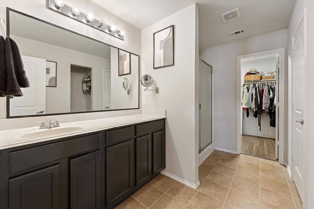 2053 Lake Trail Drive, Heartland, TX 75126 Double vanity with expansive mirror, neutral-toned cabinetry, and tiled flooring
