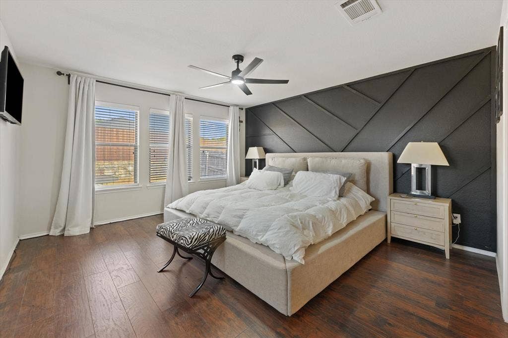 2053 Lake Trail Drive, Heartland, TX 75126 Wood-finish flooring, accent wall with geometric paneling, multiple windows with blinds, ceiling fan with integrated lighting