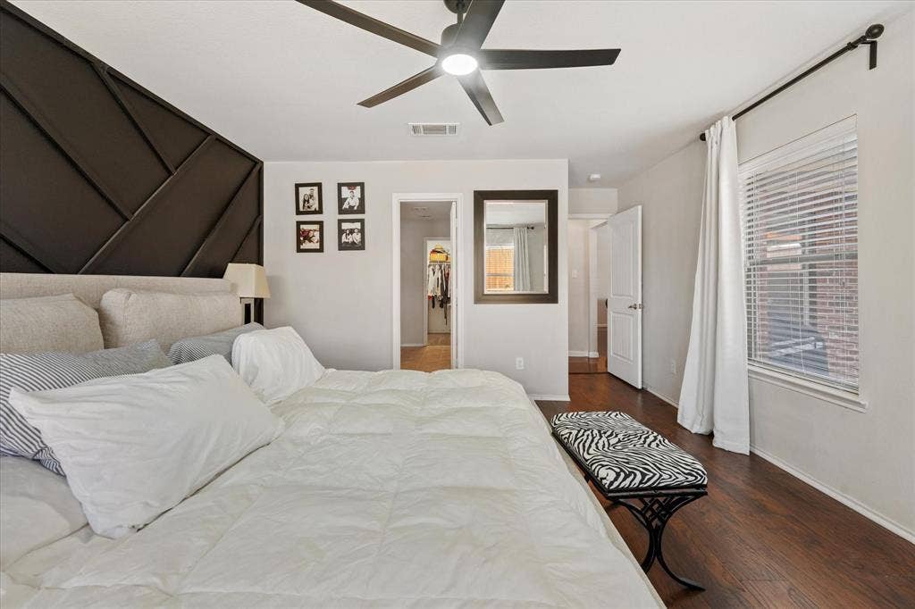 2053 Lake Trail Drive, Heartland, TX 75126 Angled geometric accent wall, wood-finish flooring, ceiling fan with integrated lighting, white window blinds, and white interior doors
