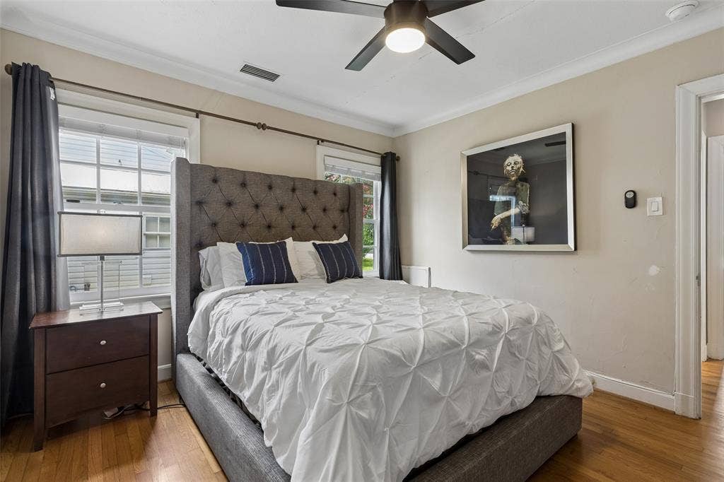 Hardwood flooring, painted walls, crown molding, and a ceiling fan with integrated lighting