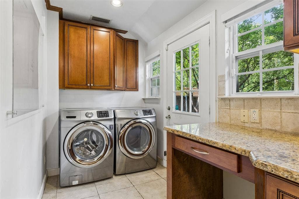 Laundry area featuring wood cabinetry, a granite-finish countertop, and tile flooring