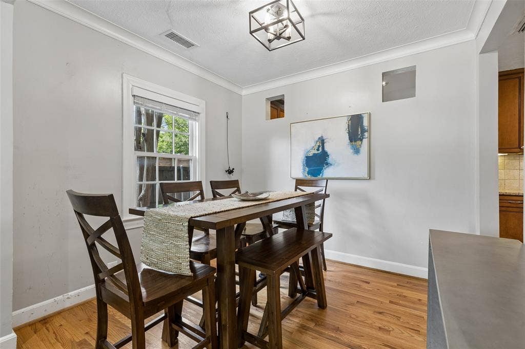 Hardwood flooring with white crown molding, a large double-hung window, and an attached ceiling fixture
