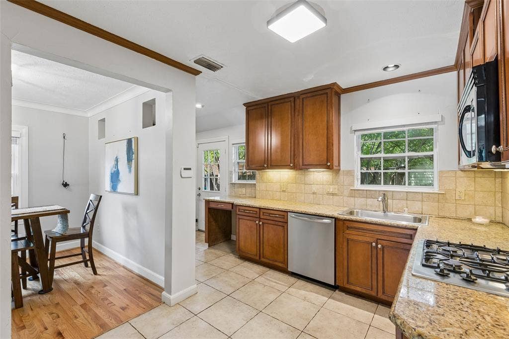 Kitchen featuring wood cabinetry, stainless steel dishwasher, tile backsplash, built-in gas cooktop, and granite countertops