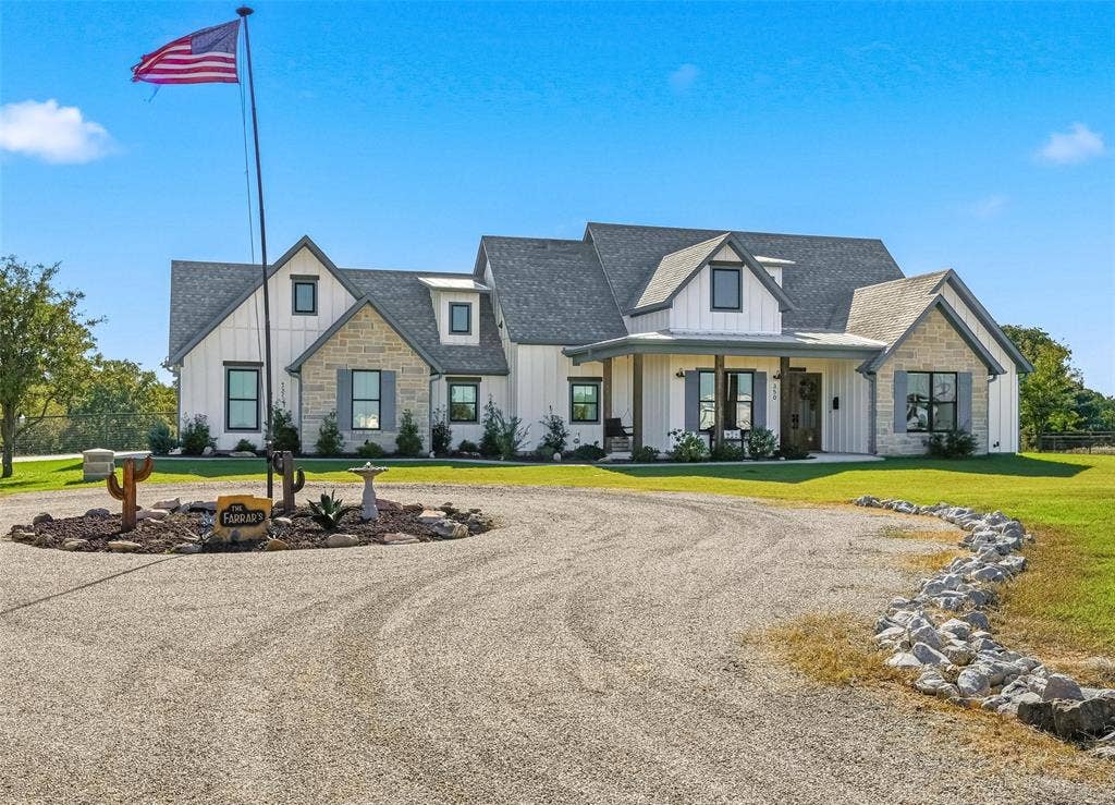 Modern inspired farmhouse with board and batten siding, stone siding, covered porch, roof with shingles, and circular driveway