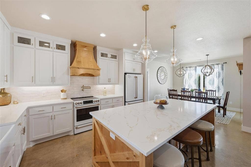 Kitchen with white cabinetry, tasteful backsplash, white appliances, a center island, and hanging light fixtures
