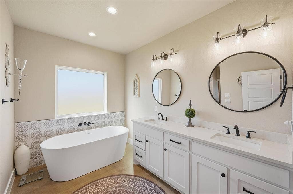 Primary Bathroom with a freestanding bath, double vanity, recessed lighting, and tile walls