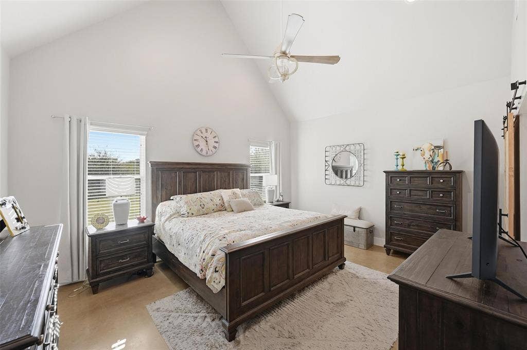 Bedroom featuring high vaulted ceiling, ceiling fan, and a barn door