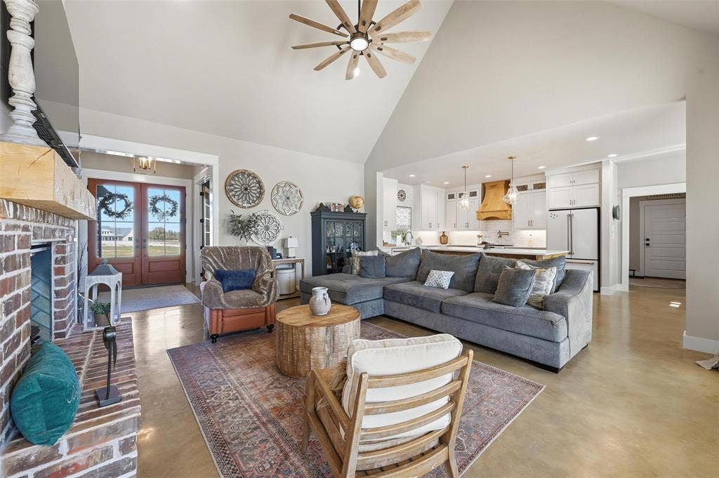 Living area featuring finished concrete floors, high vaulted ceiling, recessed lighting, a ceiling fan, and french doors
