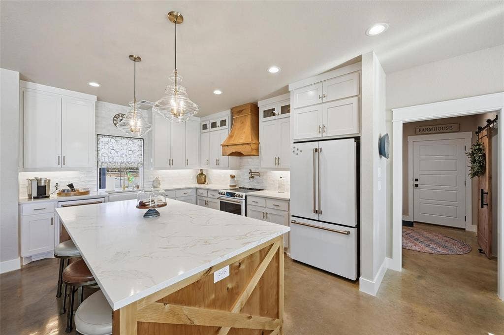 Kitchen featuring concrete floors, decorative backsplash, glass insert cabinets, white appliances, and recessed lighting